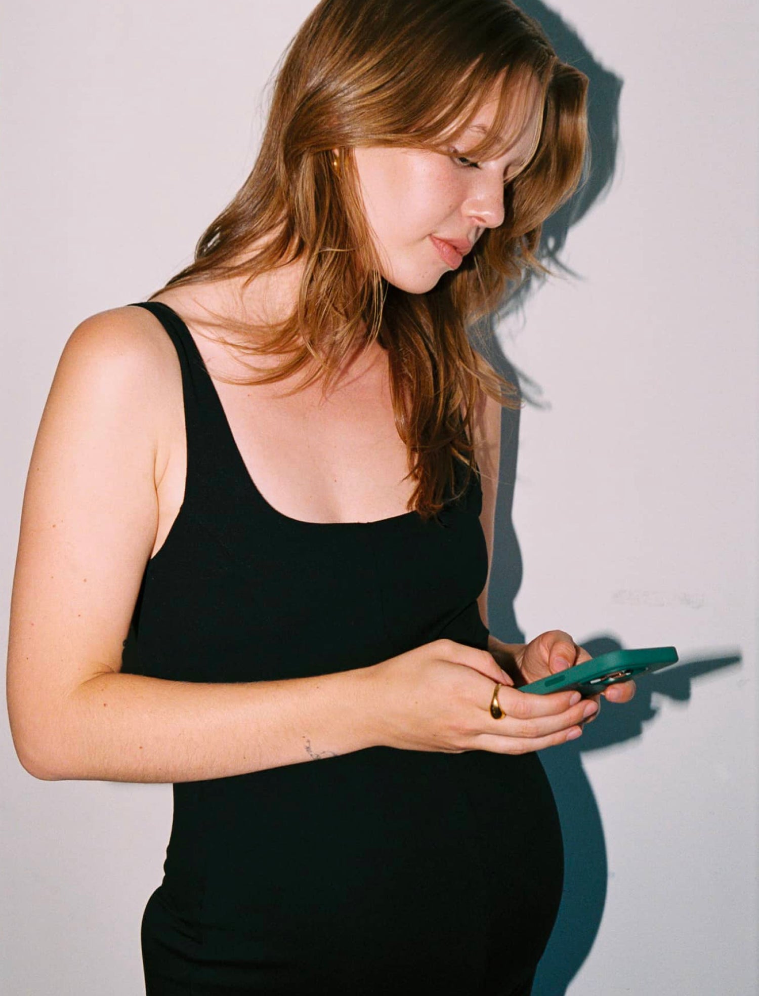 Pregnant women using her phone while wearing EMF shielding maternity wear